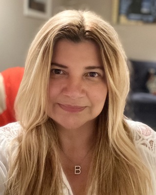 A blonde haired person wearing a gold necklace with the letter B initial.