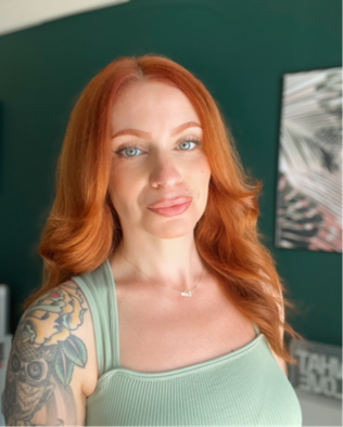 A red haired person wearing a light green tanktop shirt.
