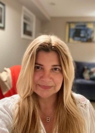 A blonde haired person wearing a gold necklace with the letter B initial.