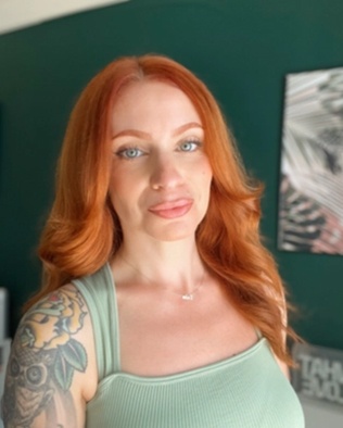 A red haired person wearing a light green tanktop shirt.
